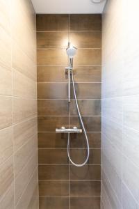 eine Dusche in einem Badezimmer mit Holzfliesen in der Unterkunft T3 avec Terrasse & Jardin Proche de la gare Alfred Musset in Clermont-Ferrand + 18 Fotos