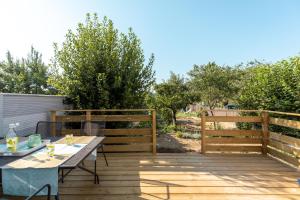 eine Holzterrasse mit einem Tisch und einem Zaun in der Unterkunft T3 avec Terrasse & Jardin Proche de la gare Alfred Musset in Clermont-Ferrand