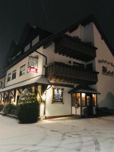 a large white building in the snow at night at Gasthof zur Post Hotel - Restaurant in Breckerfeld