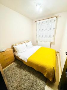 a bedroom with a yellow bed and a window at SELLADA APARTAMENT - Free Private Parking,AC,Wi-Fi in Carei