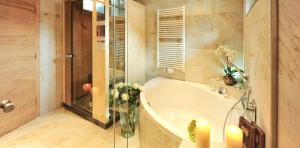 ein Badezimmer mit einer Badewanne und einer Vase aus Blumen in der Unterkunft Salnerhof Superior Lifestyle Resort in Ischgl