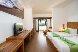 a hotel room with two beds and a flat screen tv at Sedasa Lodge in Canggu