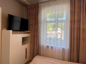 a bedroom with a large window with a television at Pod Lipami in Rewal