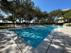 a swimming pool with blue water and trees at Residenza Cristallo in Lignano Sabbiadoro