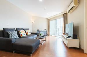 ein Wohnzimmer mit einem Sofa und einem Flachbild-TV in der Unterkunft Belle Rama9 精品公寓 in Bangkok