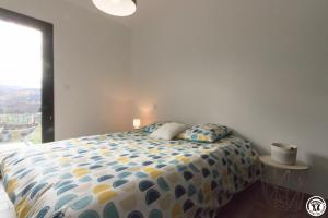 a bedroom with a bed with a blue and yellow comforter at Villa jacuzzi, terrain de pétanque et aire de jeux vue sur les Pyrénées in Seilhan