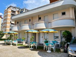 um edifício com mesas, cadeiras e guarda-sóis em Hotel Magda em Cattolica