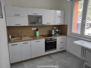 uma cozinha com armários brancos, um lavatório e um micro-ondas em Dobré místo em Loučná nad Desnou