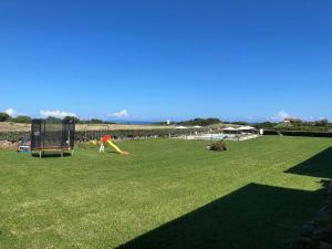 a large grassy field with a playground with a play equipment at La Casa di Spinosella in Valledoria