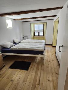 1 dormitorio con 1 cama y suelo de madera en Airolo with private parking, en Airolo