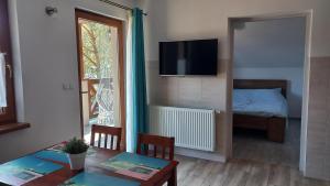 a living room with a table and a television and a bed at Apartamenty Pod Lasem in Ostrowo