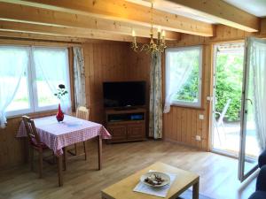 a living room with a table and a tv at Alpen Chalet in Kandersteg
