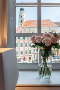 een vaas gevuld met roze rozen zittend op een vensterbank bij Hotel Forstinger - Boutique Hotel Schärding in Schärding