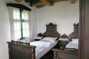 ein Schlafzimmer mit zwei Einzelbetten und zwei Fenstern in der Unterkunft Hillside View Cottage - Csíksomlyó-panoráma vendégház in Păuleni-Ciuc