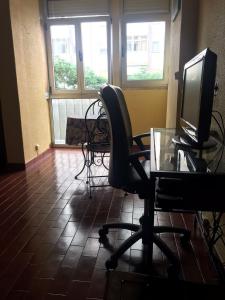 an office with a desk with a computer monitor and a chair at Estúdio a 3 min a pé da Praia de Oeiras in Paço de Arcos