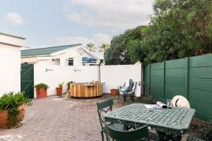 a patio with a table and chairs and a fence at Langebaan Kite Cottages in Langebaan