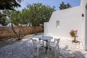 un patio con mesa, sillas y una valla en Prasino Oniro, en Tinos