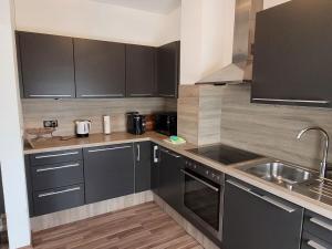 kuchnia z czarnymi szafkami i zlewem w obiekcie Zentral gelegene, sehr ruhige und helle Wohnung w Grazu +8 zdjęć