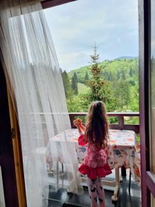 Una bambina in piedi su un balcone che guarda fuori dalla finestra di Poiana Cristian a Poiana Brasov