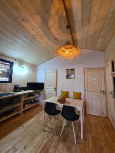 Habitación con mesa, 2 sillas y TV. en Camping Aux Couleurs du ferret, en Lège-Cap-Ferret