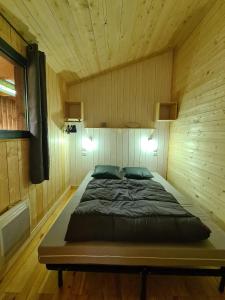 a bedroom with a bed in a wooden room at Camping Aux Couleurs du ferret in Lège-Cap-Ferret