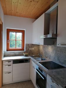 a kitchen with white cabinets and a sink and a window at Haus Obweg - Postalm in Hallein