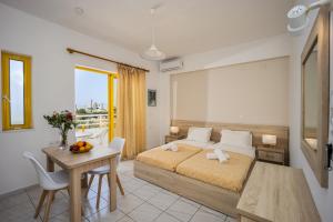 a bedroom with a bed and a table and a desk at Cosmi Apts Gouves by Estia in Gouves