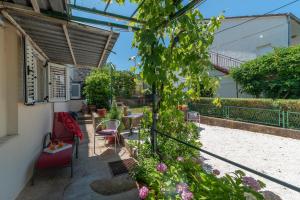 a patio with a table and chairs and flowers at Apartment Hrabar Longo in Trogir