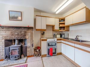 a kitchen with a brick fireplace and a stove at Coachmans Cottage - N832 in Wark