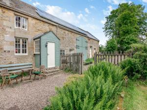 a brick building with a bench and a wooden fence at Coachmans Cottage - N832 in Wark