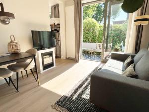 a living room with a couch and a table and a television at The East Wing Bloemendaal in Bloemendaal