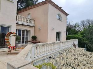 uma casa com uma cerca branca e uma cadeira numa varanda em Villa avec vue sur Sommières em Villevieille