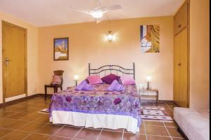 1 dormitorio con cama con sábanas moradas y almohadas moradas en Villa de Montaña gran piscina, en Sant Jordi