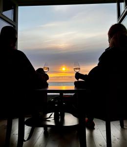 dos personas sentadas en una mesa con copas de vino en Midnattsol rom og hytter, en Bleik