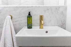 a bottle of soap sitting on top of a white sink at Malvern - By Luxury Apartments in Cheltenham