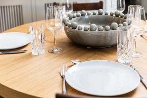 een houten tafel met borden en glazen en een kom erop bij Malvern - By Luxury Apartments in Cheltenham