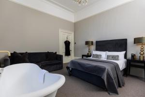 een slaapkamer met een bed en een bank bij Malvern - By Luxury Apartments in Cheltenham