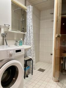 a washing machine in a bathroom with a shower at Kotimaailma Apartments near center apartment+sauna in Lahti