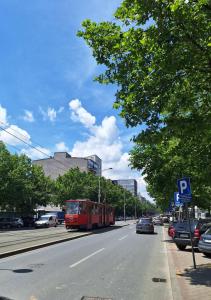 a red bus driving down a city street with cars at Apartment Nataly in Vračar (historical)