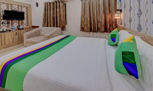 um quarto com uma grande cama branca e uma cadeira em Treebo Trend Seven Inn em Tirupati