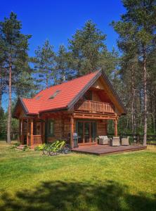 Cabaña de madera con techo rojo en un campo en Hankówka Mazury, en Jerutki