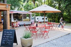 a patio with tables and chairs and an umbrella at Huttopia Millau in Millau