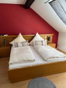a bed with white pillows and a red wall at Gasthof zur Post Hotel - Restaurant in Breckerfeld