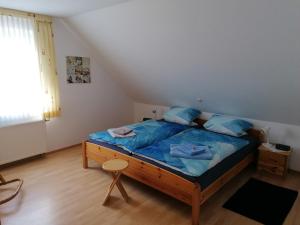 Schlafzimmer mit einem Bett mit blauer Bettwäsche und einem Fenster in der Unterkunft Ferienwohnung Gebken in Börgerwald