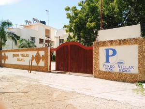 una valla con un cartel que lee villas de pago bebe playa en Pendo Villas Diani Beach en Diani Beach