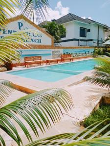a swimming pool with benches in front of a building at Pendo Villas Diani Beach in Diani Beach