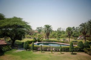 a swimming pool in a garden with trees and bushes at Clarks Safari Pushkar in Pushkar