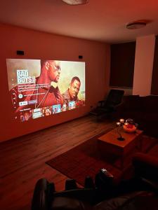 a living room with a large screen tv in a living room at Cinema Relax Apartament in Pristina