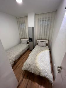 Habitación con 2 camas, paredes blancas y suelo de madera. en Cinema Relax Apartament en Pristina