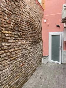 una pared de ladrillo con una puerta blanca al lado de un edificio en La Divina Holiday, en Rávena